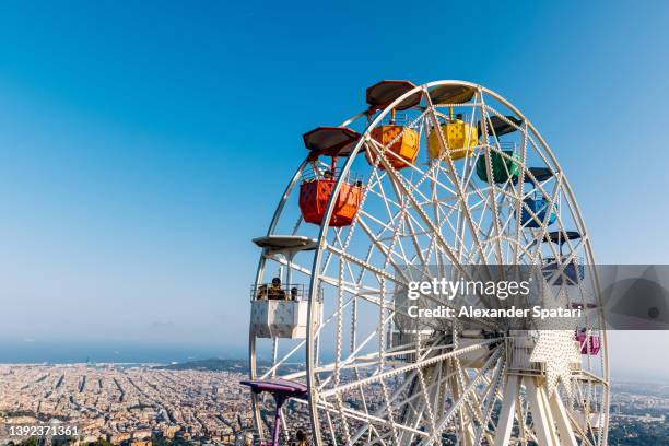 multicolored ferris wheel at tibidabo and barcelona skyline, high angle view, barcelona, spain - tibidabo fotografías e imágenes de stock