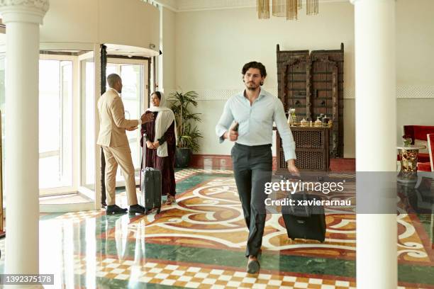 businessman with luggage walking through riyadh hotel - global entry stock pictures, royalty-free photos & images