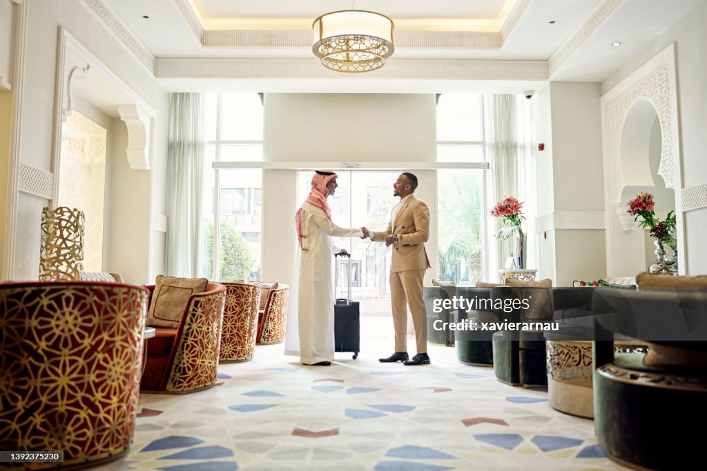 Saudi businessman shaking hands with client in hotel lobby