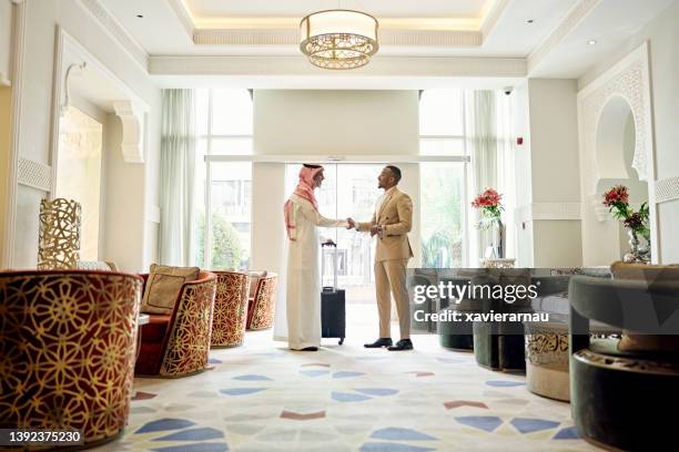 saudi businessman shaking hands with client in hotel lobby - países do golfo pérsico imagens e fotografias de stock