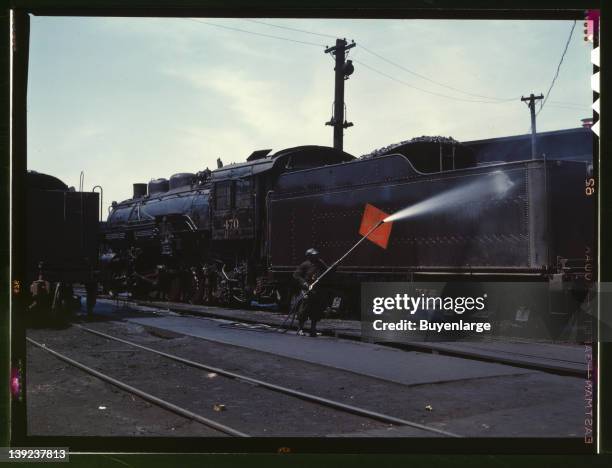 Cleaning an engine near the roundhouse, Chicago, Milwaukee, St. Paul and Pacific Railroad & Pennsylvania Railroad yard, Bensonville, Illinois, 1943.
