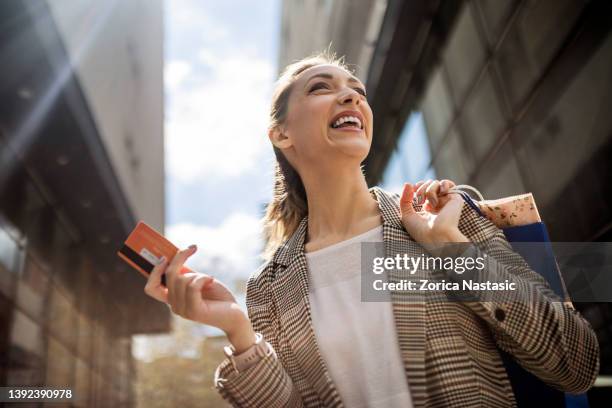 young woman holding shopping bags shopping in the city with credit card - credit card stock pictures, royalty-free photos & images