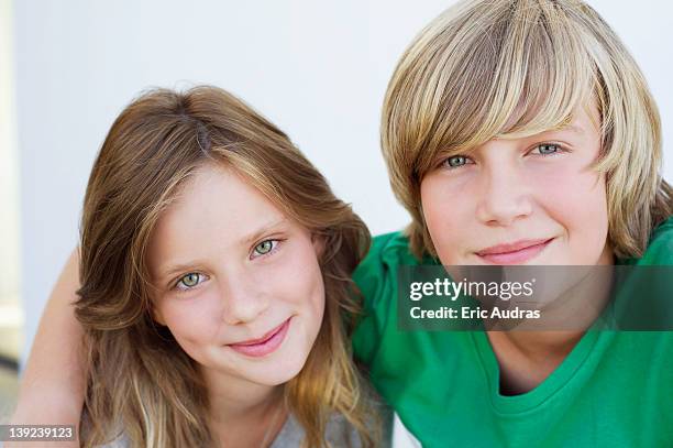 portrait of a teenage boy smiling with his sister - girl sitting on boys face fotografías e imágenes de stock