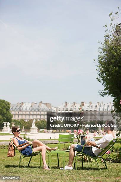 man using a laptop with a woman sitting in front of him, jardin des tuileries, paris, ile-de-france, france - jardín de las tullerías fotografías e imágenes de stock