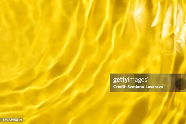 closeup of clear water surface texture with splashes and bubbles. trendy abstract nature background. ripple water texture on yellow background. - water ripple stock-fotos und bilder