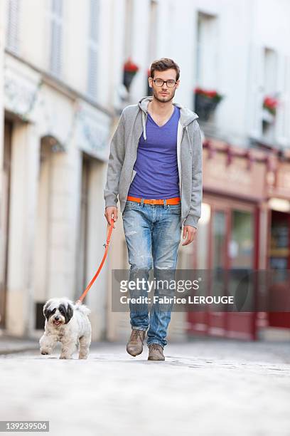 man holding a dog on leash walking on the street, paris, ile-de-france, france - ile de france ストックフォトと画像