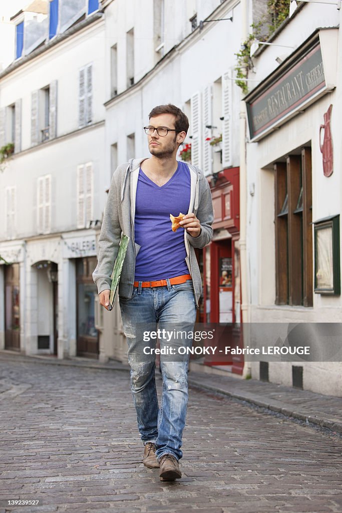 Man carrying a file while eating food, Paris, Ile-de-France, France