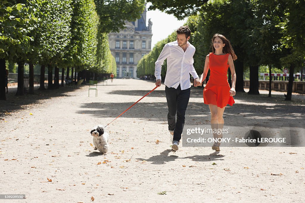 Couple running in a garden with a puppy, Terrasse De l'Orangerie, Jardin des Tuileries, Paris, Ile-de-France, France
