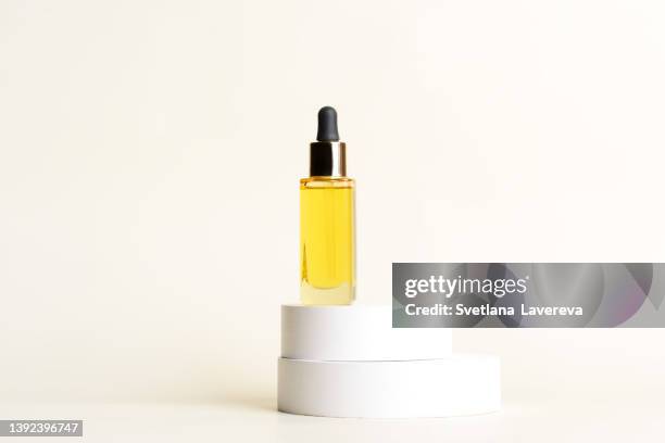 a glass dropper bottle with a pipette with black rubber tip on the white round circle podiums on the light beige background. nature skin concept. organic spa cosmetics. trendy concept. - cosmetic jar stockfoto's en -beelden