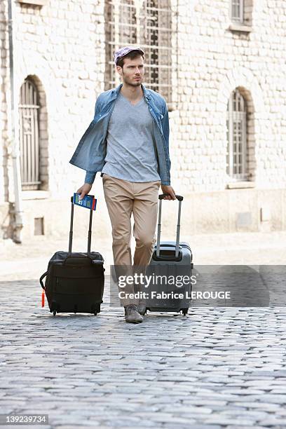 man pulling trolley bags on the road, paris, ile-de-france, france - carry on luggage photos et images de collection