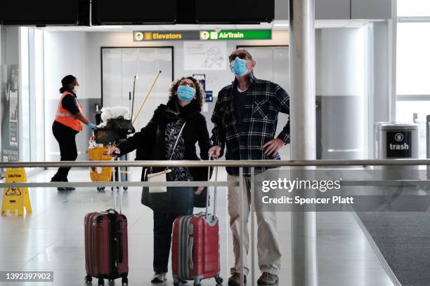 Travelers wearing masks look up at a sign inside John F. Kennedy Airport on April 19, 2022 in New York City. On Monday, a federal judge in Florida...