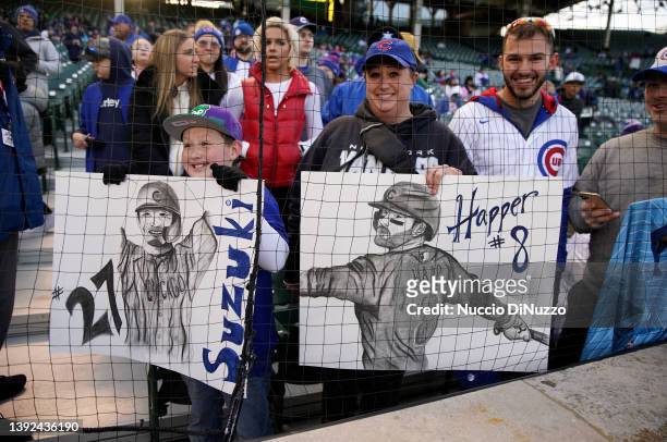 Young fans hold signs bearing the likenesses of Seiya Suzuki and Ian Happ of the Chicago Cubs prior to a game against the Tampa Bay Rays at Wrigley...