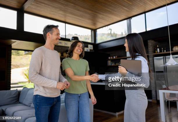 real estate agent handshaking with a couple of customers - selling house stockfoto's en -beelden