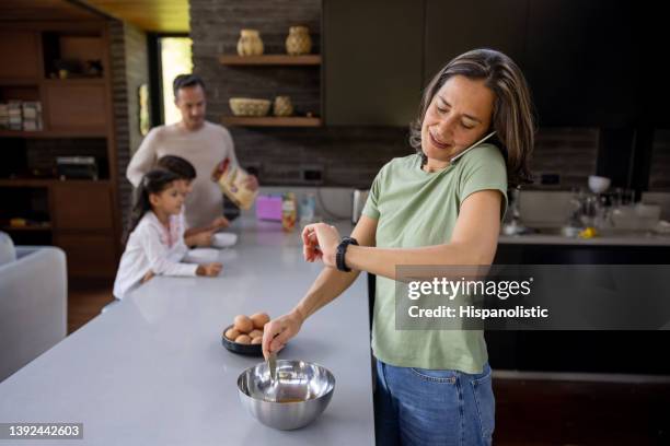 busy mother multi-tasking at home in the morning while preparing breakfast - checking the time stock pictures, royalty-free photos & images