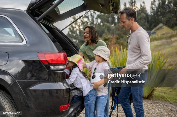 happy family going on a road trip and getting the bags in the trunk - family car stock pictures, royalty-free photos & images