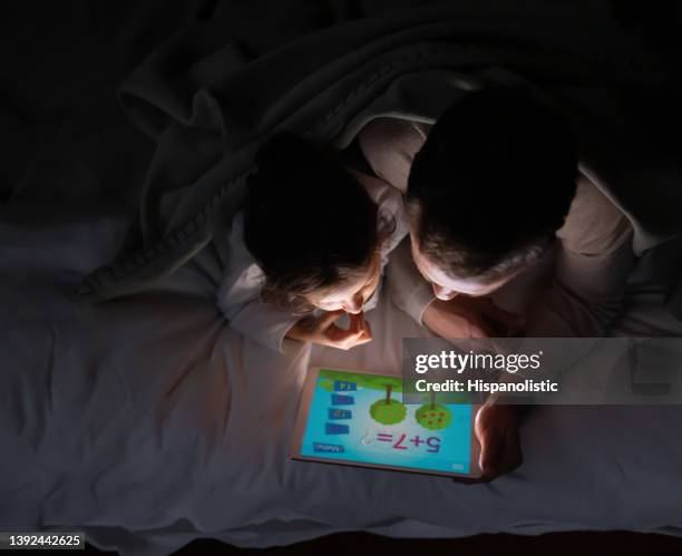 happy kids playing games on a tablet in bed - children ipad stock pictures, royalty-free photos & images