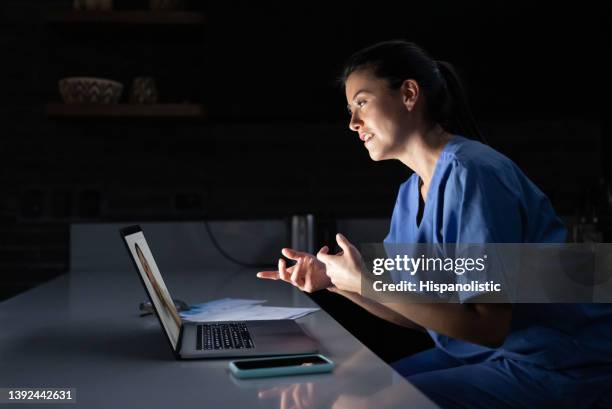 doctor working late at home and talking to a patient on a video call - virtual visit stock pictures, royalty-free photos & images