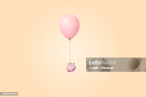 pink piggy bank tied to a balloon - balloons concept imagens e fotografias de stock