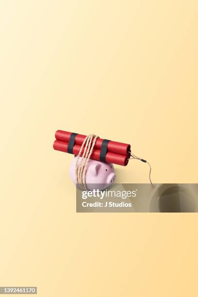 piggy bank tied to a dynamite stick - market volatility stock pictures, royalty-free photos & images