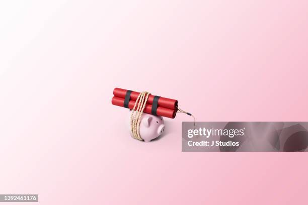 piggy bank tied to a bundle of dynamite sticks - stock market crash stock pictures, royalty-free photos & images