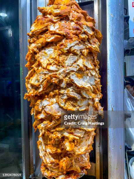 vertical column of chicken kebab roasting on a spit. juicy marinated chicken and sometimes lamb rotating on spit and once cooked thinly sliced and served with bread and salad or in a wrap. traditional snack and junk food after alcohol and big party. - doner kebab stock pictures, royalty-free photos & images