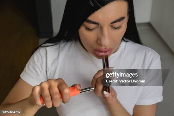 beautiful young woman smoking medical marijuana using glass smoking pipe - human joint stockfoto's en -beelden