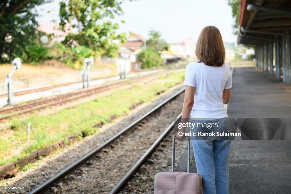 Rear view of woman standing at railroad station