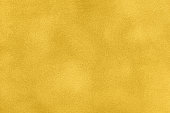 Background of yellow suede matte fabric closeup. Velvet matt texture of golden nubuck textile. Velveteen pattern.