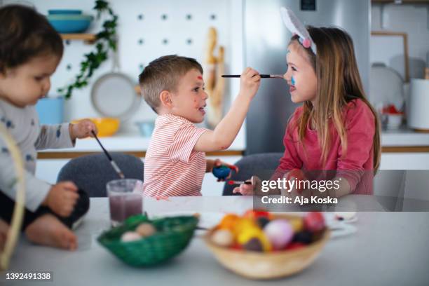 siblings painting easter eggs together. - dirty easter stock pictures, royalty-free photos & images
