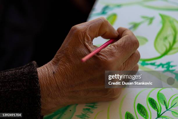 old wrinkled hand holding paintbrush - painters hands stock pictures, royalty-free photos & images