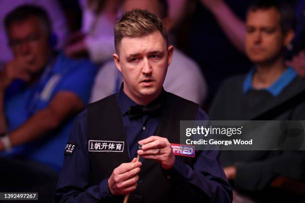 Kyren Wilson of England chalks the cue during the Betfred World Snooker Championship Round One match between Kyren Wilson of England and Ding Junhui...