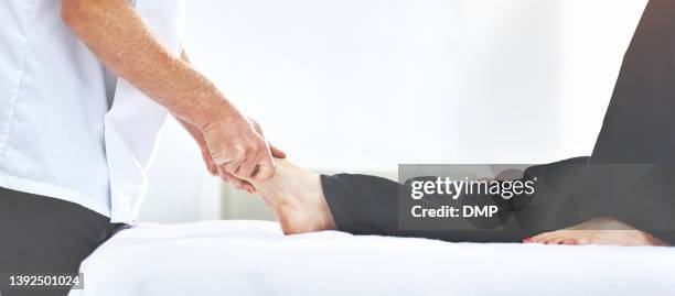 colpo di un fisioterapista che massaggia il piede di un cliente - osteopata foto e immagini stock