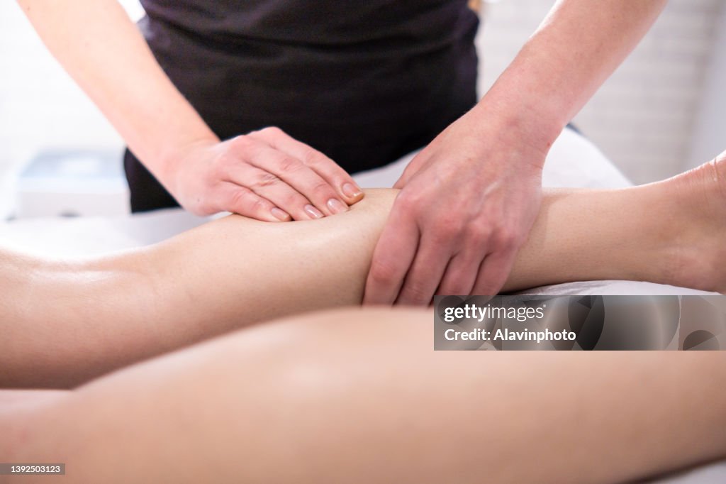 Female physiotherapist giving calf massage to a woman lying on a stretcher