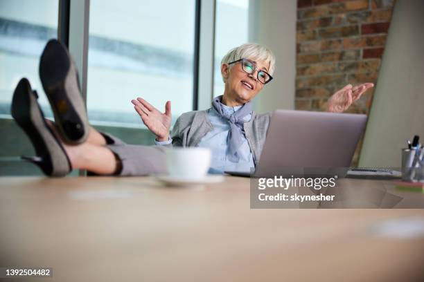 relaxed mature businesswoman having a video call in the office. - feet on table bildbanksfoton och bilder