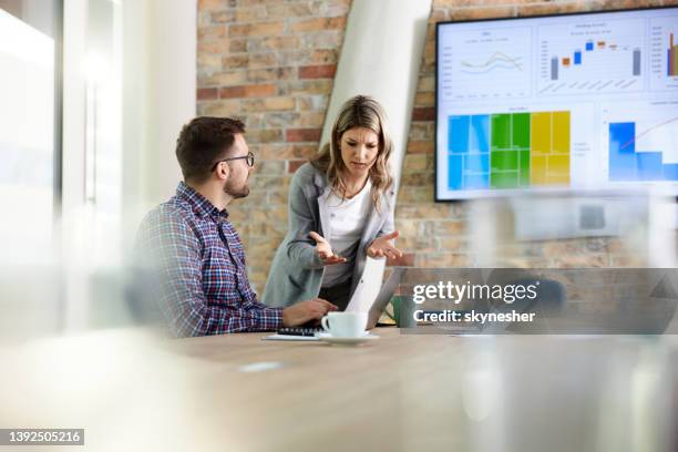 young business colleagues talking while using laptop in the office. - two people arguing stock pictures, royalty-free photos & images