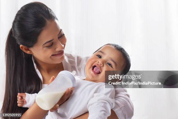 mother feeding her little baby with bottle at home - baby bottle stockfoto's en -beelden