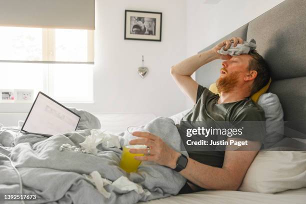 mature man lying in bed suffering from a flu-like respiratory illness - erkältung und grippe stock-fotos und bilder