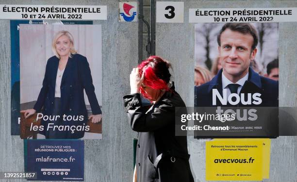 Woman walks past official campaign posters of Marine Le Pen, leader of the far-right Rassemblement national party and French President Emmanuel...