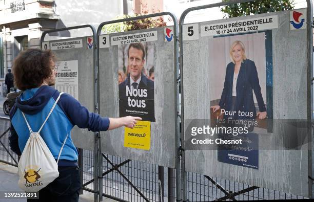 Man looks at official campaign posters of Marine Le Pen, leader of the far-right Rassemblement national party and French President Emmanuel Macron...