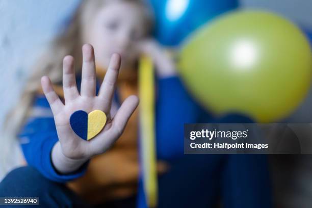 sad ukrainian immigrant child with balloons waiting at train station, ukrainian war concept. - orphan train stock pictures, royalty-free photos & images