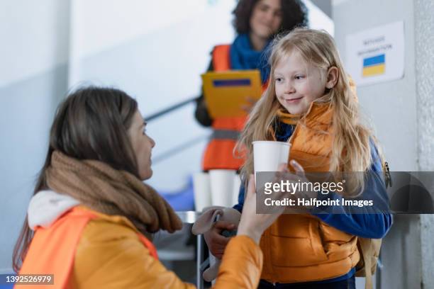 volunteers giving drink to ukrainian refugee child at train station. - resident fotografías e imágenes de stock