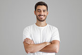 Portrait of smiling handsome man in white t-shirt, standing with crossed arms
