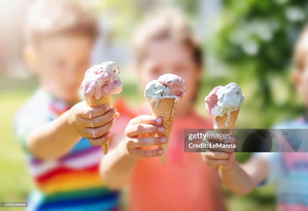 Group of children in the park eating cold ice cream.