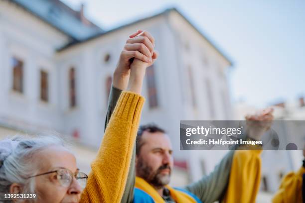 people holding hands and protesting against russian invasion in ukraine in streets. - demonstratie stockfoto's en -beelden