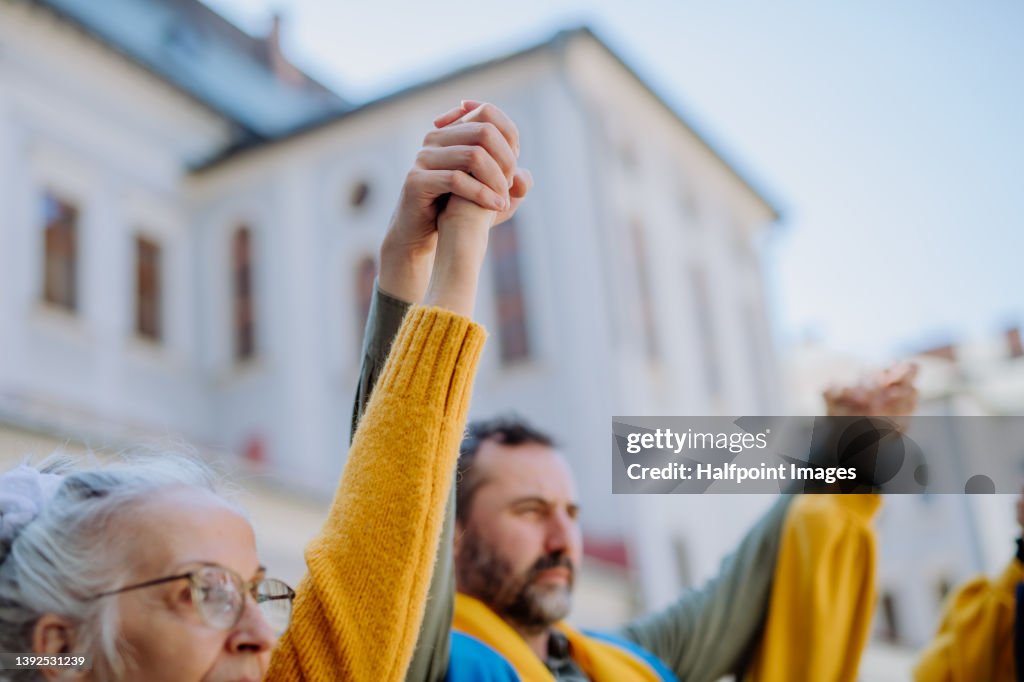 People holding hands and protesting against Russian invasion in Ukraine in streets.