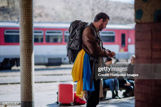 sad man with ukrainian flag on train station. - refugees stockfoto's en -beelden