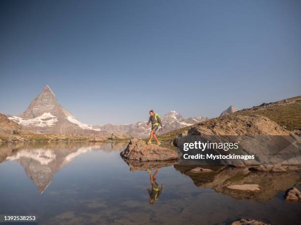 mann springt auf alpensee von fels zu fels - zermatt stock-fotos und bilder