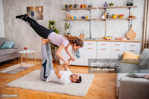 jeune couple faisant de l’acroyoga à la maison - acrobatic activity photos et images de collection
