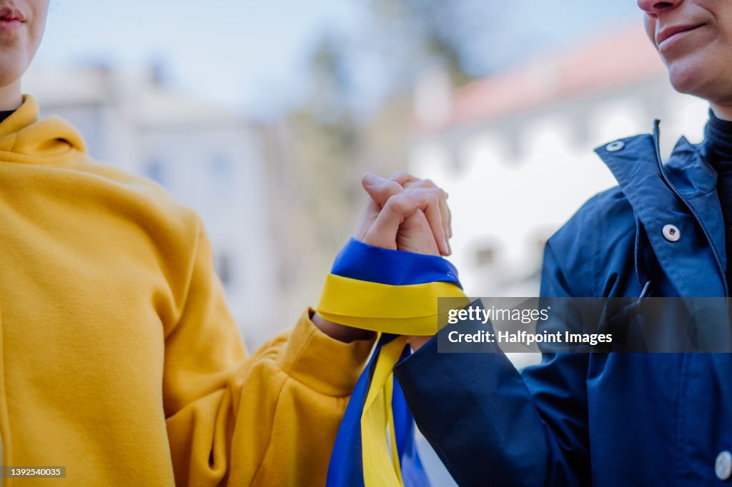 People holding hands and protesting against Russian invasion in Ukraine in streets.
