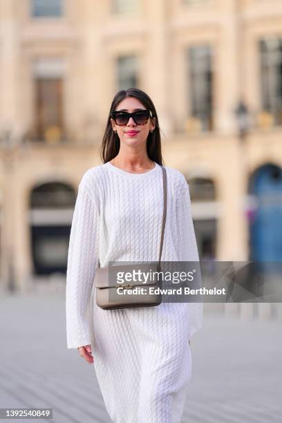 Bianca Derhy wears black sunglasses from Celine, gold and rhinestones earrings, gold chain necklaces, a white embossed braided wool pattern oversized...
